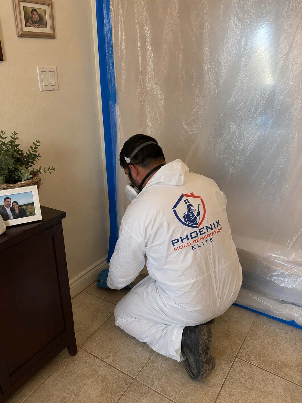 Mold remediation contractor in full PPE installing containment barriers